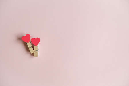 Two red hearts on a clothespin on a gently pink background. View from above. Valentine's day...