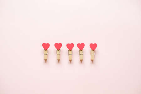 Five clothespins with hearts on a pink backgroundの写真素材