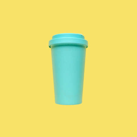 Turquoise bamboo coffee mug on a yellow background without shadows. Environmental consumption, care for the world, recycling. Isolateの写真素材