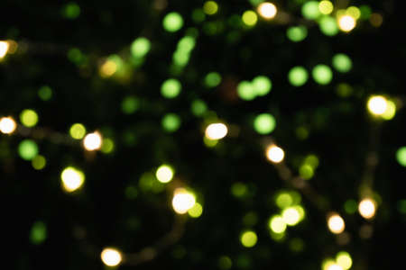 Bokeh of yellow and green lights. Sequins on dark background. Christmas decorations