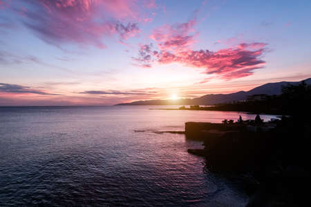 Beautiful dawn on the sea. Shades of coral, pink and purple in the sunlight and morning sky.の写真素材