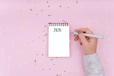 The inscription is in a white notebook. Woman writes plans for next year. Beautiful pink background...