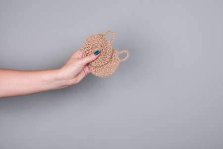 Knitted eco washcloths for washing dishes on a gray background in a womans hand. Zero waste conceptの写真素材