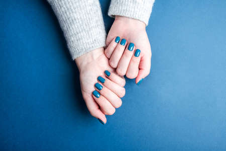 Beautiful womens hands with a neat blue manicure. Main color conceptの写真素材