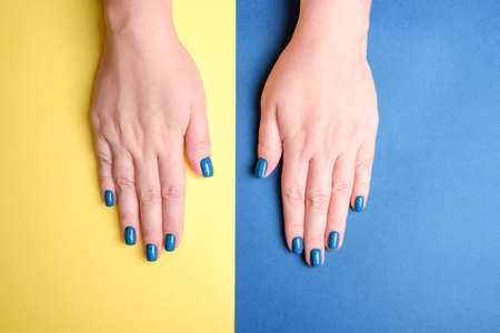 Beautiful womens hands with a neat manicure blue on a yellow background.の写真素材