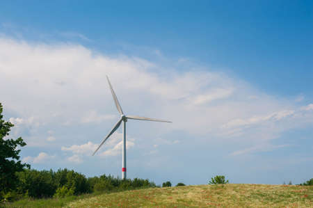 Windmills against the blue sky. Poppy and chamomile fields of Europe. The concept of eco-friendly electricity.の写真素材