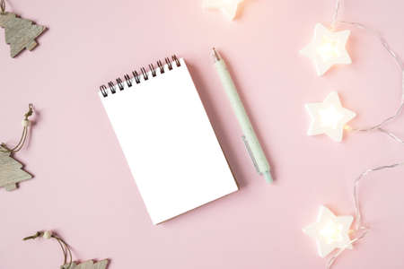 White sheet, pen and a plant on a pink background. The concept of planning and recording goals for the new year. Top view of stationery and Christmas. Place for your textの写真素材