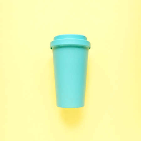 Turquoise bamboo coffee mug on yellow background. Environmental consumption, care for the world, recyclingの写真素材