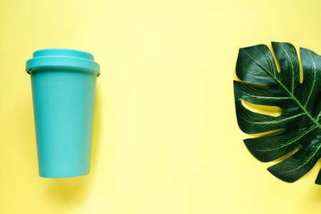 Coffee and tea glass mint color on a yellow background. Top view of the plant and Cup. The concept of a drink to go and safe consumptionの写真素材