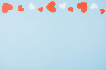 Blue background with red and white paper hearts. Space for text