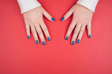 Stylish womens manicure on a red background. Beautiful well-groomed hands after you go to a salon.の写真素材