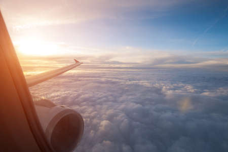 Beautiful cumulus clouds under the wing of an airplane. Flight to a warm country. Return home from travelの写真素材
