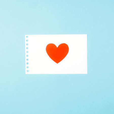 Delicate blue background with a white Notepad sheet and a heart. Valentine's day messageの写真素材