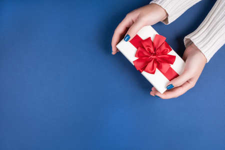 Gift box with a red bow in womens hands. Birthday present. Promotion gifts when buying.Blue...
