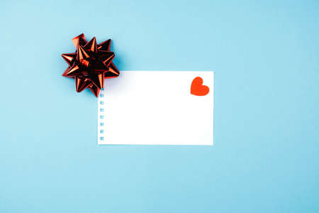 Delicate blue background with a white Notepad sheet and a heart. Valentines day messageの写真素材