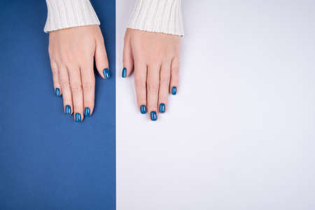 Stylish women's manicure on a blue-gray background. Fashionable women's manicure in blue. Stylish manicure, great design for any purposes. Health care concept.の写真素材