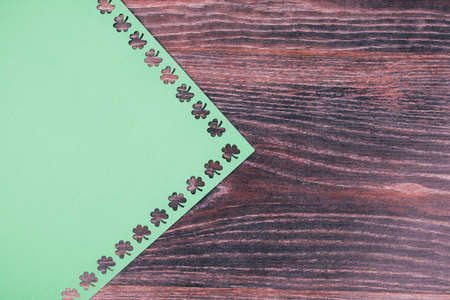 Background for St. Patrick's day. Green cardboard with a stencil of clover leaves. Space for text