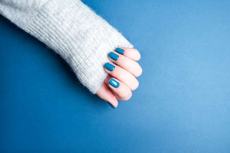 Beautiful female manicure on a blue background. Blue manicure on well-groomed hands.の写真素材