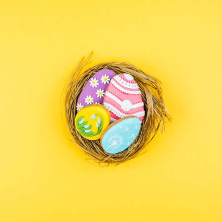 Nest with Easter eggs on a yellow background. Cookies decorated with Easter eggs. Stylish background for Easter.の写真素材