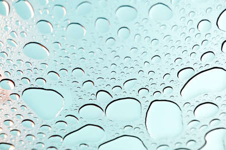Blue sky with raindrops on the glass. Beautiful mint-colored background of water. Beautiful blurred...