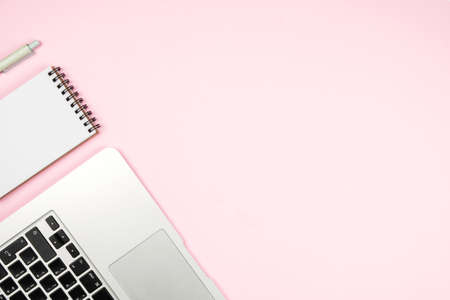 Laptop and Notepad with a pen on a pink background. Photo in minimalism style, space for text, top view. Flat lay.の写真素材