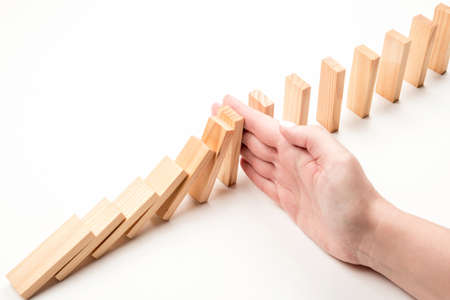 Hand stops falling wooden blocks. Crisis inhibition concept.の写真素材
