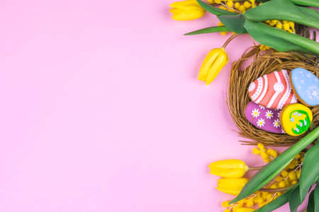 Easter cookies and yellow tulips on a pink background. Place for text