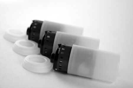 Black and white image of three film canisters lined up opened with film partially removed.の写真素材