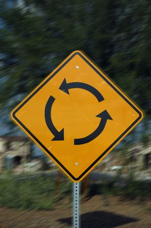 Image of a traffic circle sign with motion blur added for effect.  Represents circular logic, confusion or futile effort.の写真素材