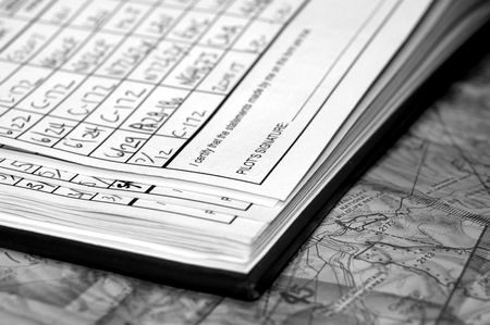 Private Airplane Pilot logbook with full page of entries showing date, airplane and airports on navigational chart. Shallow depth of field in black & white.の写真素材