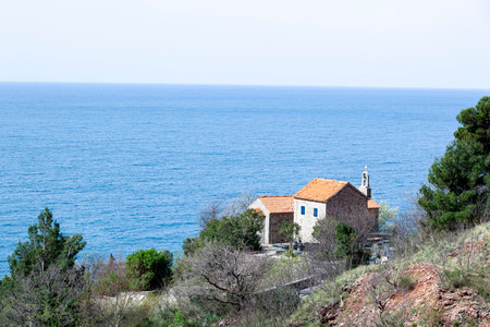 Bells on a stone monastery with an orange roof against a backdrop of sea and mountains. Monastery in Montenegro.の写真素材