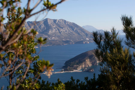 Winter sea colorful landscape with blue water of the Adriatic Sea and the island of St. Nikola near the town of Budva in Montenegro. View from above through the trees. horizontalの写真素材