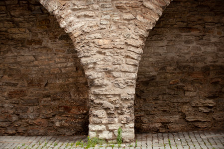 Old brick wall with semicircular arches. Weathered surface of the wall. Grunge style brick wall background. Weathered facade of a building. Horizontal.の写真素材