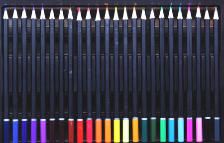 Top view of a complete set of colored pencils with black barrels, neatly arranged in a pencil case. The pencils are arranged in a color gradient, emphasizing symmetry, order, and color variety. Ideal for art, education, design, and creativity.の写真素材