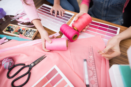 On the table lie threads, scissors, patterns of color. The photo shows children's and women's hands.の写真素材