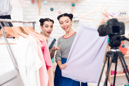 Two fashion blogger girls in jeans and shirt with skirt present colorful dress to camera.の写真素材