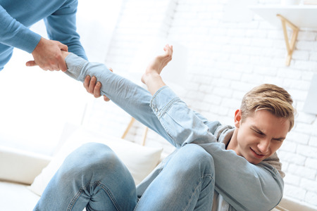 Father tries to pull up his son but troubled teenager resists his attempts. Father stands above his sitting son.の写真素材