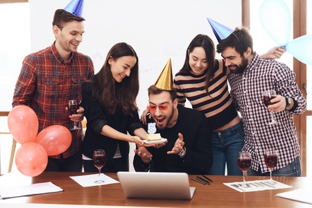 A group of office employees celebrate the fifth anniversary of their company. They are dressed in holiday caps. They are smiling.の写真素材