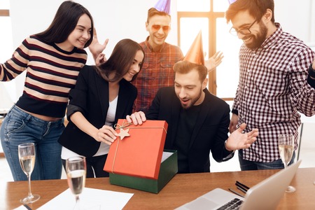 The office staff surprises their manager. They celebrate the anniversary of the company. They are dressed in holiday caps.の写真素材