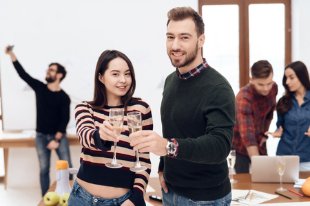A young couple celebrates at a corporate celebration. They hold glasses with champagne in their hands.の写真素材