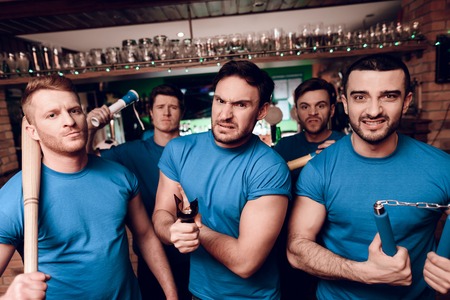 Five aggressive sports fans hooligans at sports bar. They are supporting blue team.の写真素材