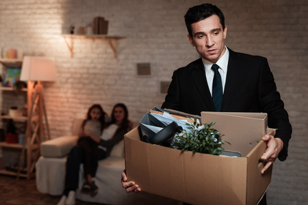 Adult man leaves family with stuff box. Father leaves home because of problems in family. Family problems. Businessman is carrying box.の写真素材