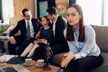 Frustrated mother in blue shit sits on couch next to adult father and daughter. Dissolution of marriage of two adults. Divorce of adult couple.の写真素材