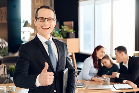 Confident adult man in suit stands in front of office of family lawyer and thumb up. Young cuople decide who will be main guardian of little child.