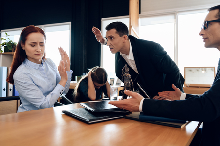 Adult man raised hand to woman with child in lawyer's office. Adult couple is divorced. Break up of two adult people.の写真素材