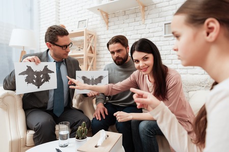 Little girl pass Rorschach test together with her parents in office of family psychiatrist. Family at acceptance with family psychologist.の写真素材