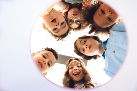 Bottom view. Surprised children look in round gift box. Concept of children's holiday. Kids are celebrating birthday party.の写真素材