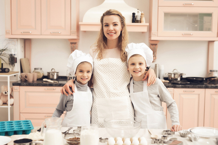 Children in chef's hats with mother in kitchen. Family is going to cook.の写真素材