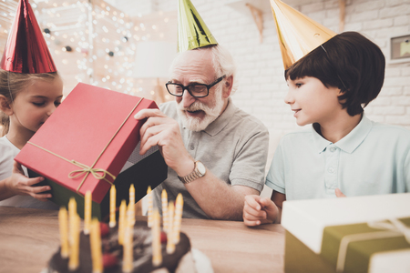 Grandfather, grandson and granddaughter at table at home. Birthday party.の写真素材