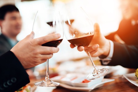 Close up. Meeting with chinese businessmen in suits in restaurant. Men are toasting with wine glasses.の写真素材